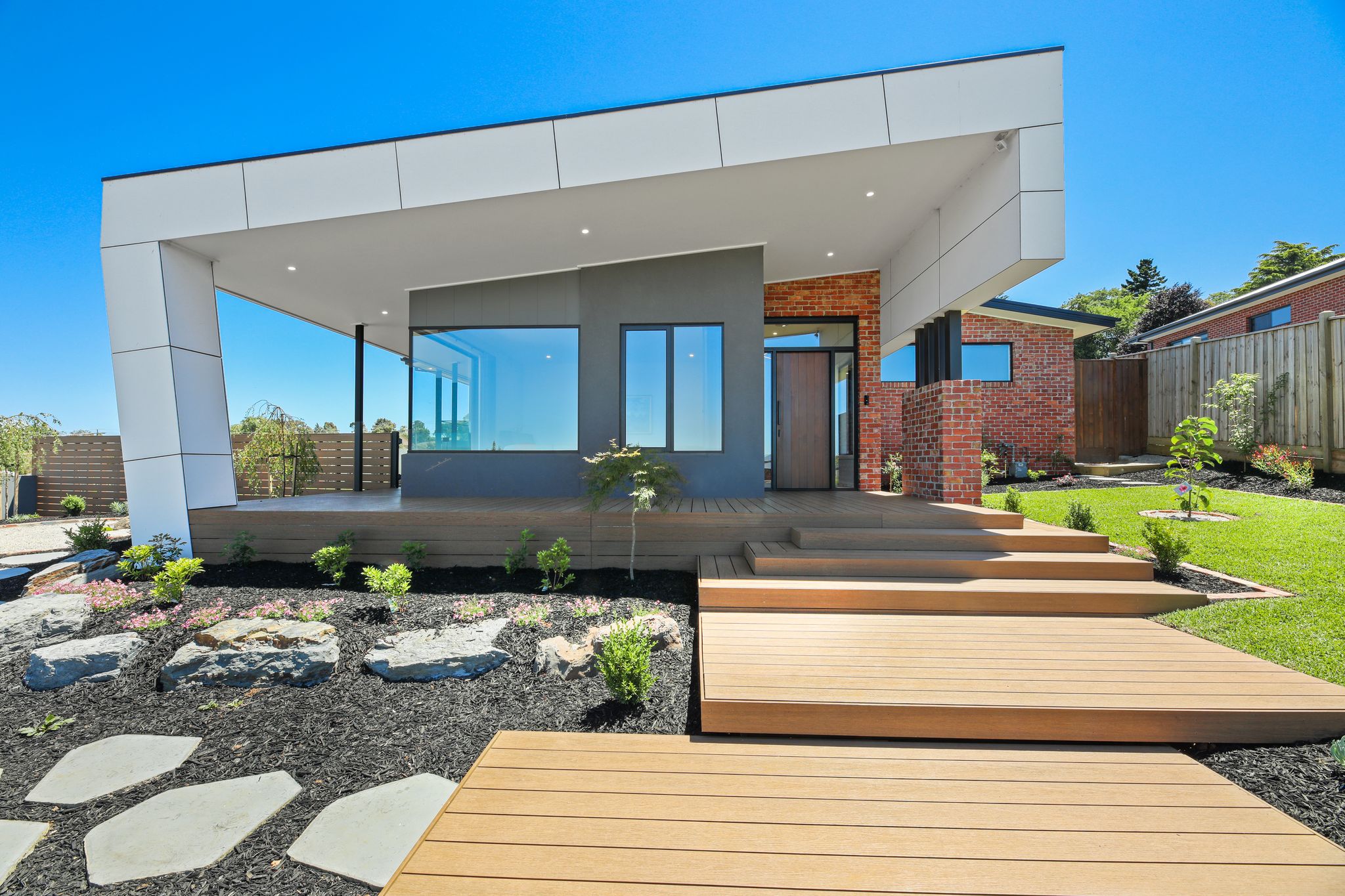 Stylish modern home featuring premium composite decking with integrated garden landscaping, showcasing sleek design and durable outdoor living solutions.