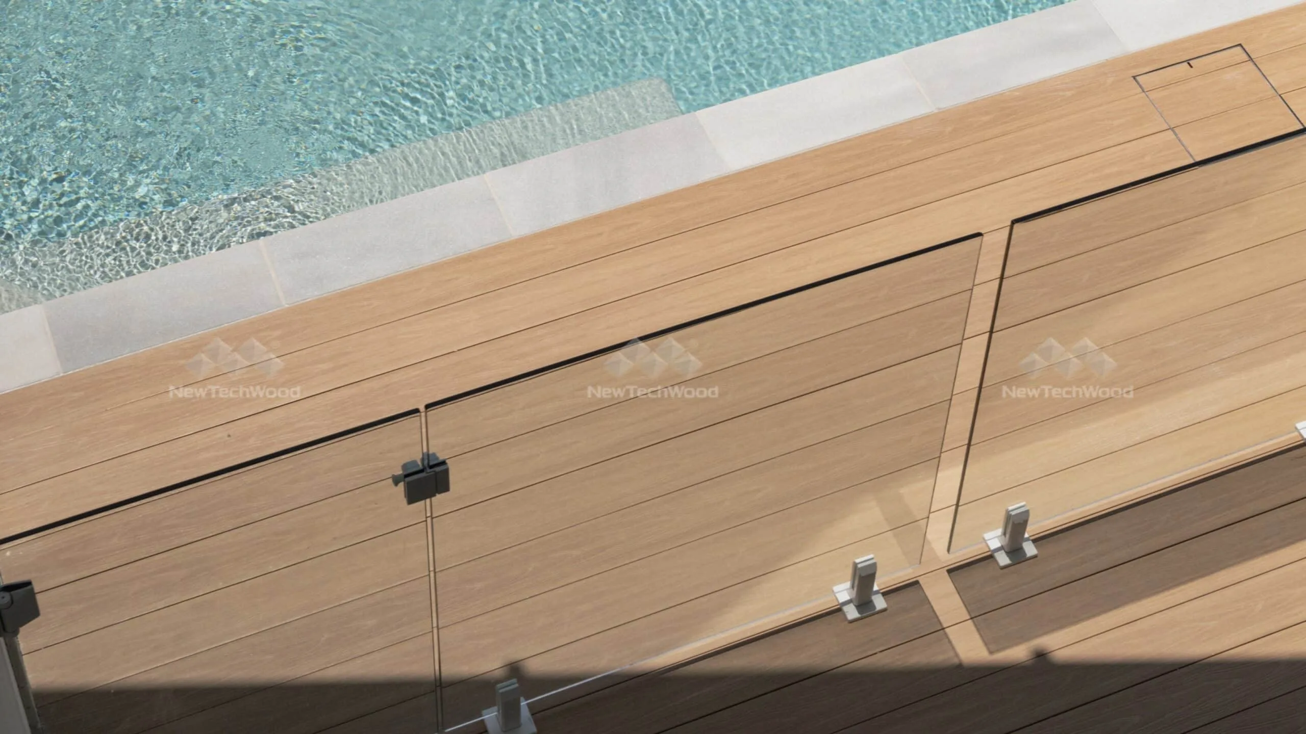 NewTechWood composite decking with a glass pool fence, providing a seamless transition to the swimming pool area.