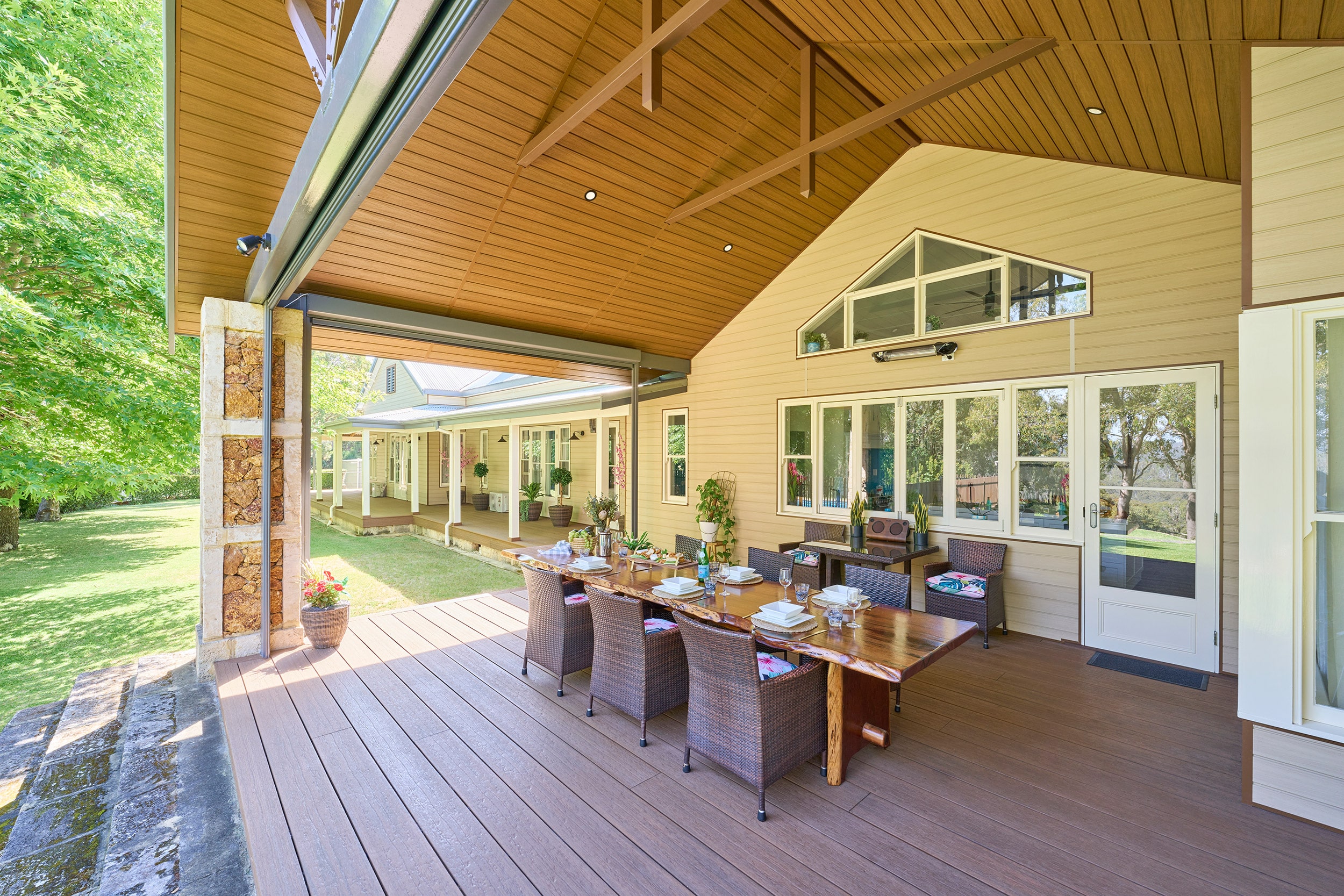 Modern composite decking in a luxurious outdoor patio setup featuring a large dining table, surrounded by a well-maintained garden, ideal for contemporary home exteriors.