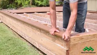Installation process of modern composite decking, showcasing hands securing the durable decking material on a wooden frame in a backyard setting, perfect for home improvement enthusiasts.