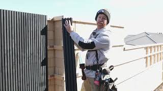Professional installer securing castellation cladding panels with visible fasteners at a construction site, demonstrating quality and expertise.