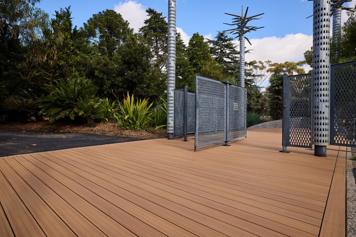 Spacious outdoor deck with natural wood tones and modern metal accents in a lush garden setting.