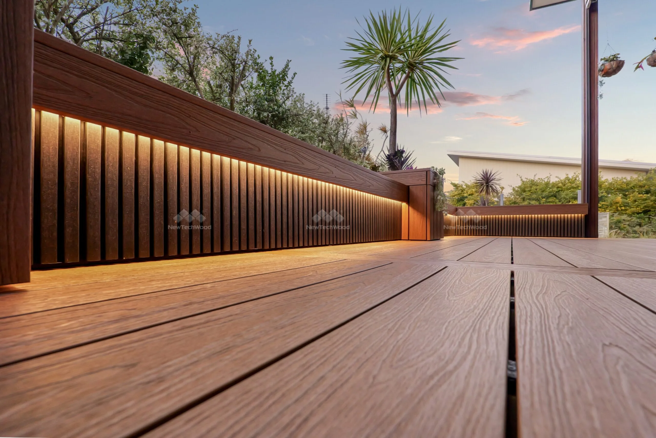 A contemporary composite fence with vertical NewTechWood panels, complemented by tropical plants and modern landscaping elements.